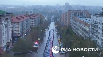 Молодежь Донецка развернула в центре города 200-метровый флаг ДНР ко Дню республиканского символа, передает корреспондент РИА Новости