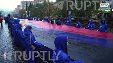 «Символ нашей Родины, нашего региона»: молодежь Донецка развернула в центре города 200-метровый флаг ДНР ко Дню республиканского символа